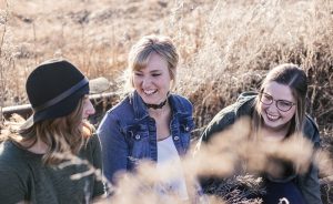 three women smiling in a field