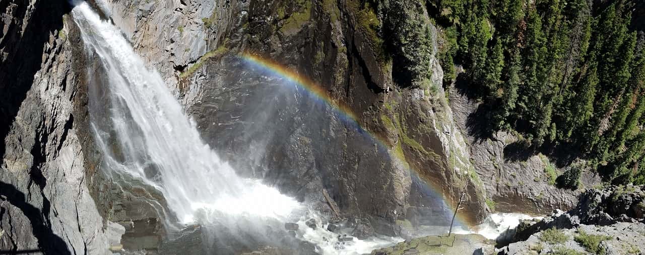 Waterfall rainbow in a steep, narrow canyon.