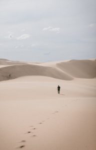 man walking through sand dunes