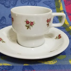 A white cup and saucer with red rosebuds on them