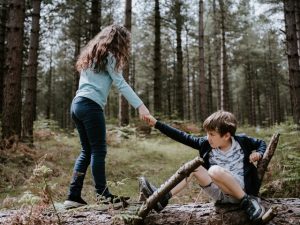 Girl lending hand to help boy get up from the ground