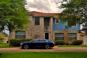 new car in front of large house