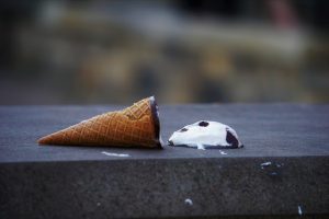 ice dream cone on its side with the ice cream melting next to the cone