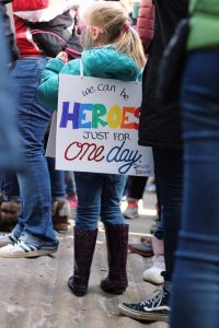 girl wearing sign says We can be HEROS just for one day