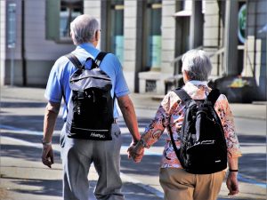 older couple with backpacks holding hands