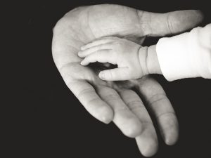 baby's hand resting in an adult's palm