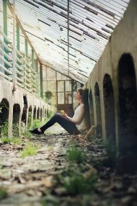 woman sitting in empty building under glass ceiling